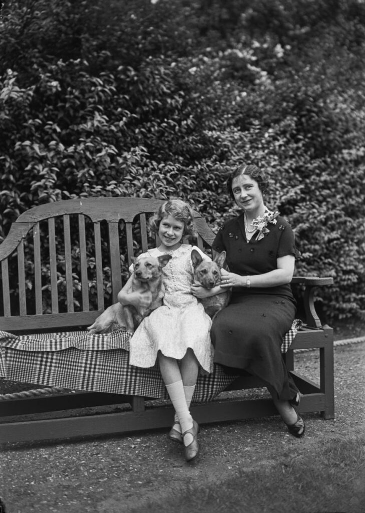 Принцесса Елизавета со своей матерью Елизаветой Боуз-Лайон (королева-мать, 1900 - 2002) и их собаками вельш-корги-пемброк Дуки и Джейн в ее доме на Пикадилли 145, Лондон, Великобритания, июль 1936 года.